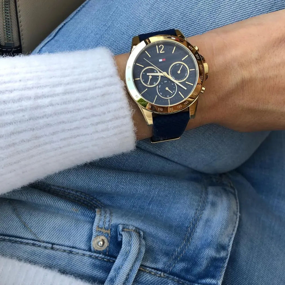 Zegarek Tommy Hilfiger na granatowym skórzanym pasku ze złotą kopertą prezentowany na nadgarstku.